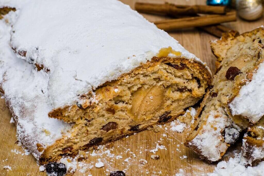 Angeschnittener veganer Christstollen auf einem Holzbrett.