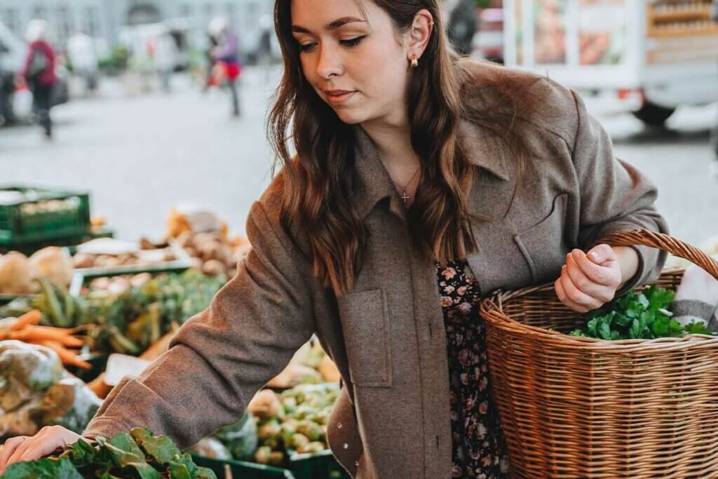 Frau kauft auf Wochenmarkt Gemuese