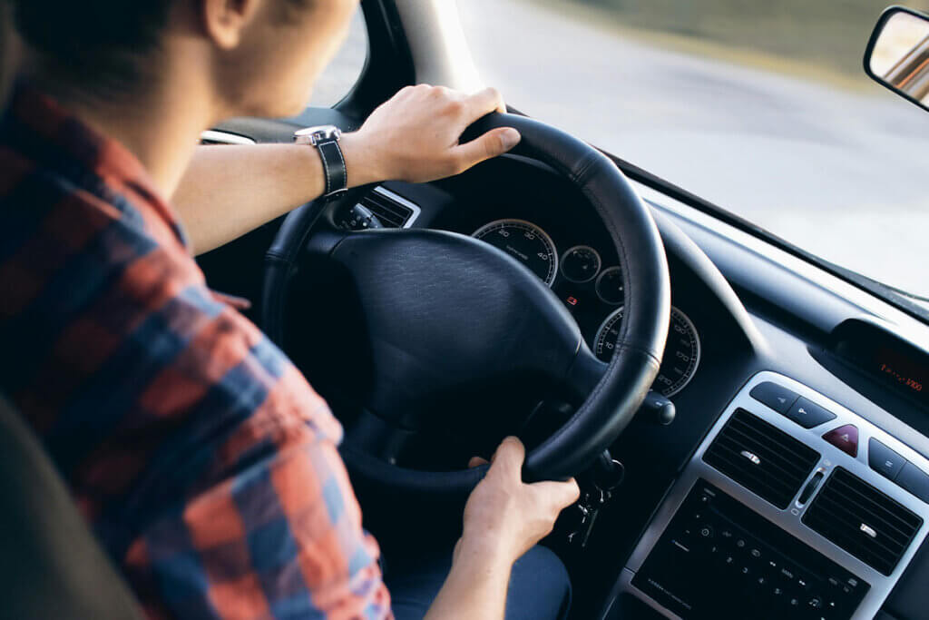 Eine Person sitzt am Lenkrad eines Autos.