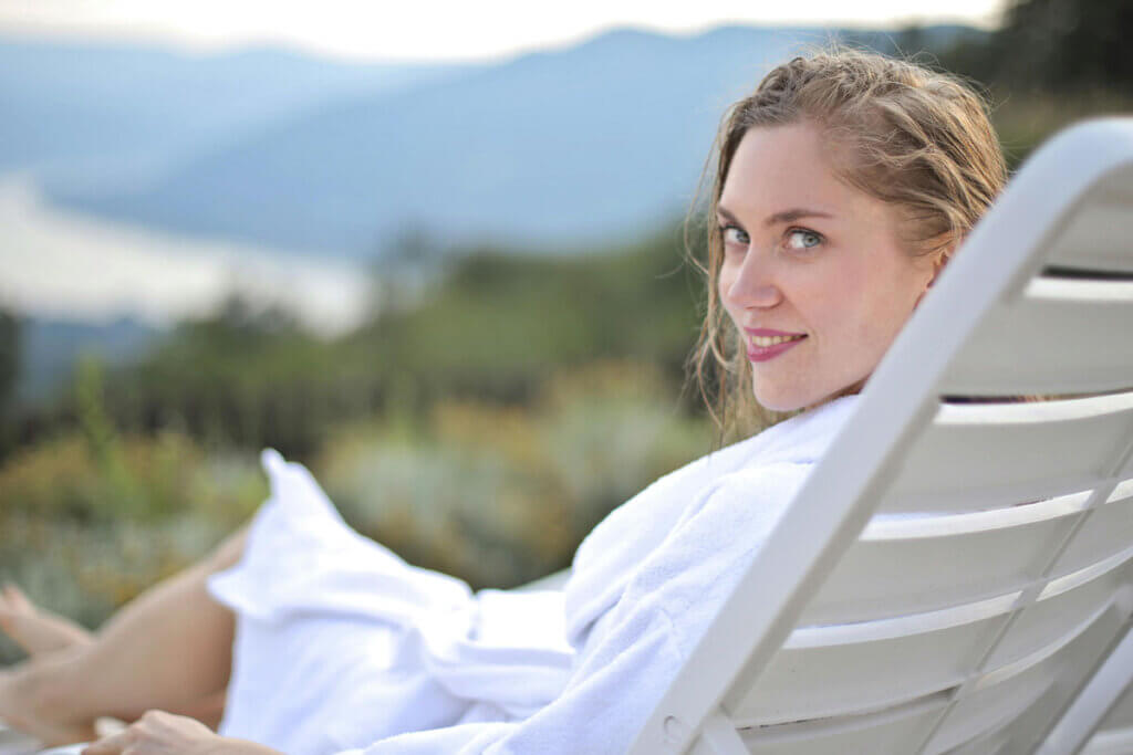 Eine Frau liegt auf einer Liege vor einem Waldpanorama in einem Hotel.